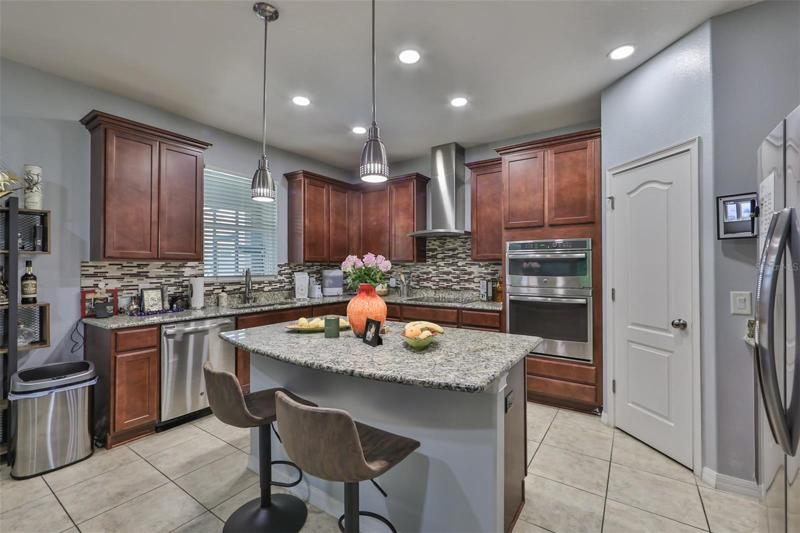 Kitchen with stainless steel apliance, ecessed lighting and decorative pendant lights, granite countertops, a large pantry closet and a large island/breakfast bar making for the ultimate gathering space.