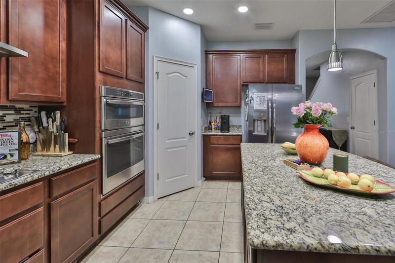 Kitchen with stainless steel apliance, recessed lighting and decorative pendant lights, granite countertops, a large pantry closet and a large island/breakfast bar making for the ultimate gathering space.