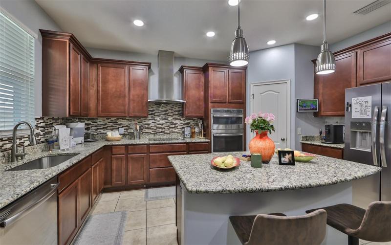 Kitchen with stainless steel apliance, recessed lighting and decorative pendant lights, granite countertops, a large pantry closet and a large island/breakfast bar making for the ultimate gathering space.