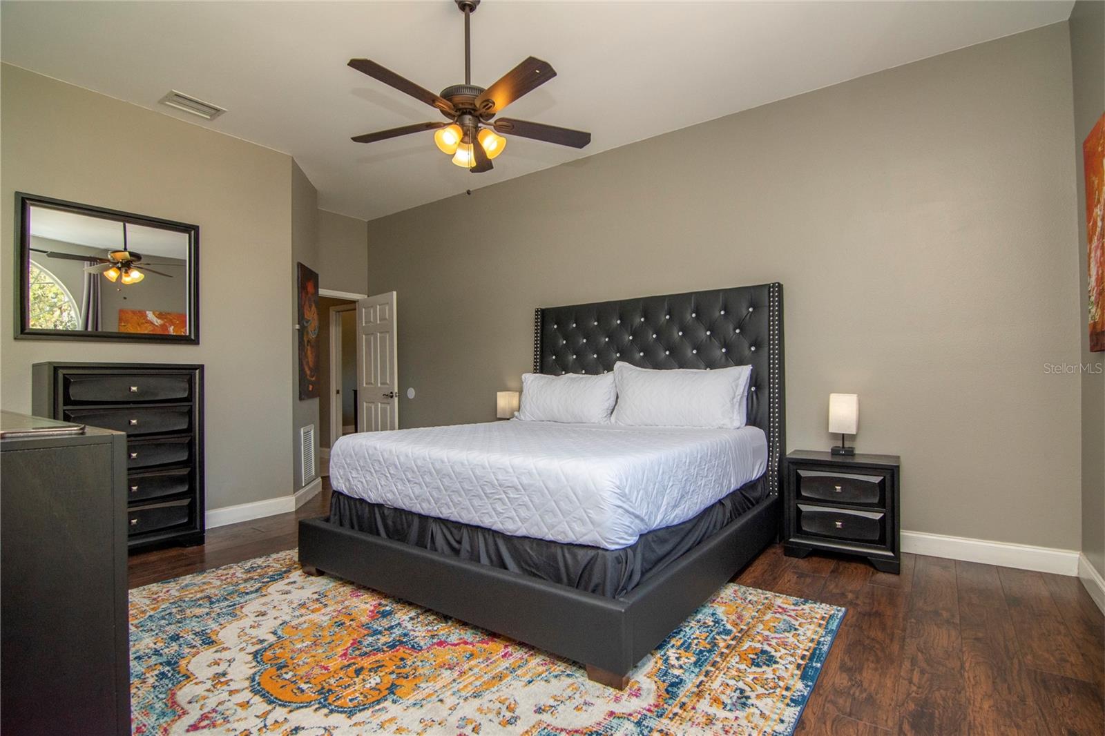 Third bedroom with lighted ceiling fan, full ensuite bathroom. Furniture is negotiable, including king size bed with hotel quality mattress and box springs, matching dresser and matching nightstands/lights, rug, mounted smart TV and artwork.