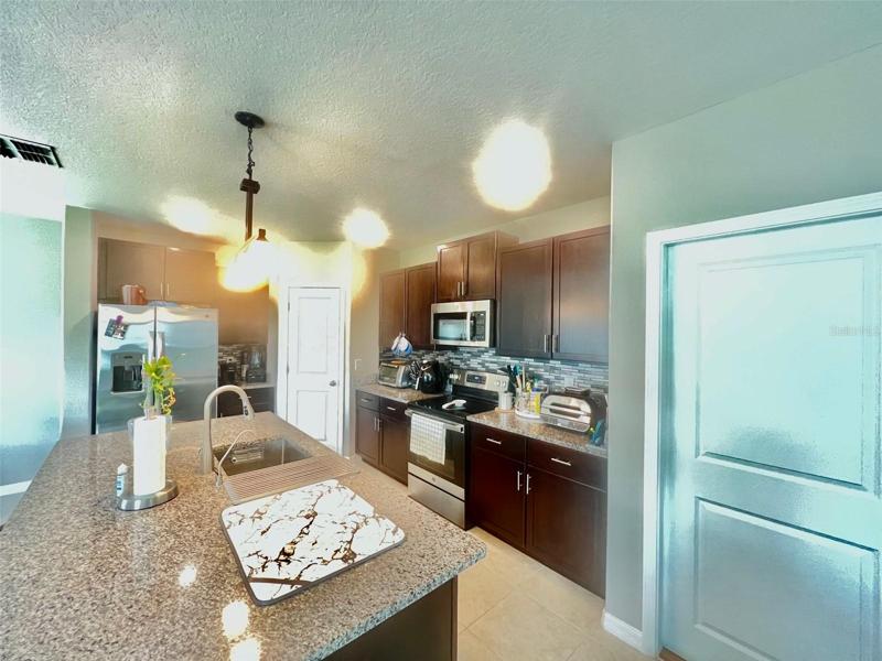 Kitchen with large granite island countter top and beautiful backsplash