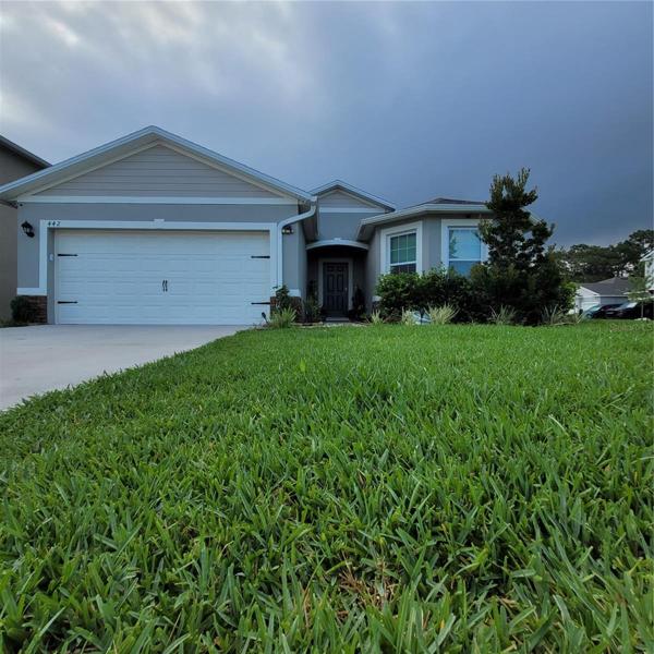 Front showing rain gutters, bay window and manicured landscaping.