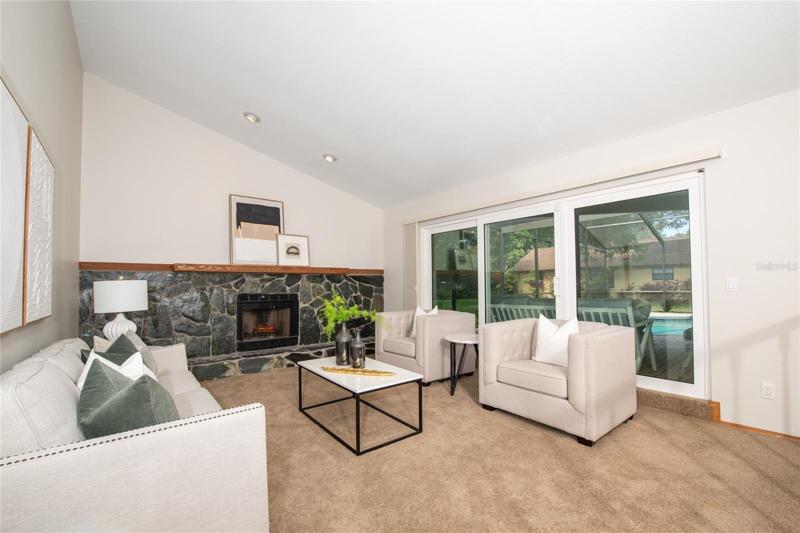 Vaulted ceiling Living area with wood burning fireplace.  Impact sliding doors open to the lanai and pool area.Freshly painted inside,too!