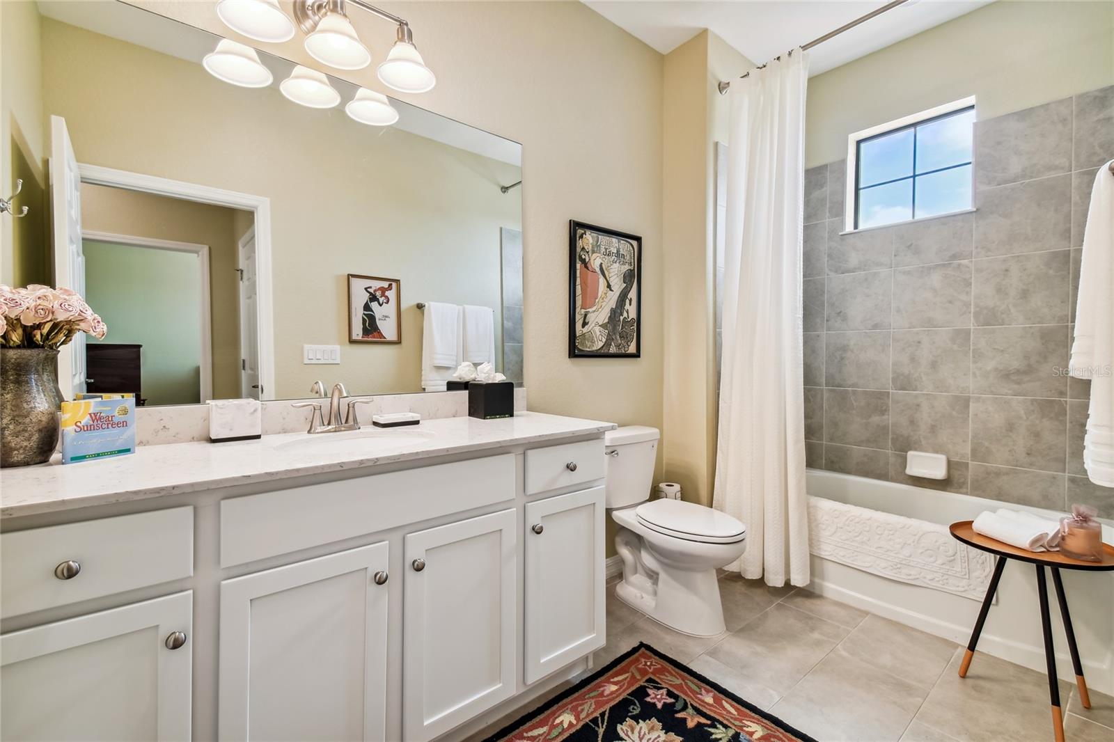 very large second bathroom with stationery window, single sink and tub/shower