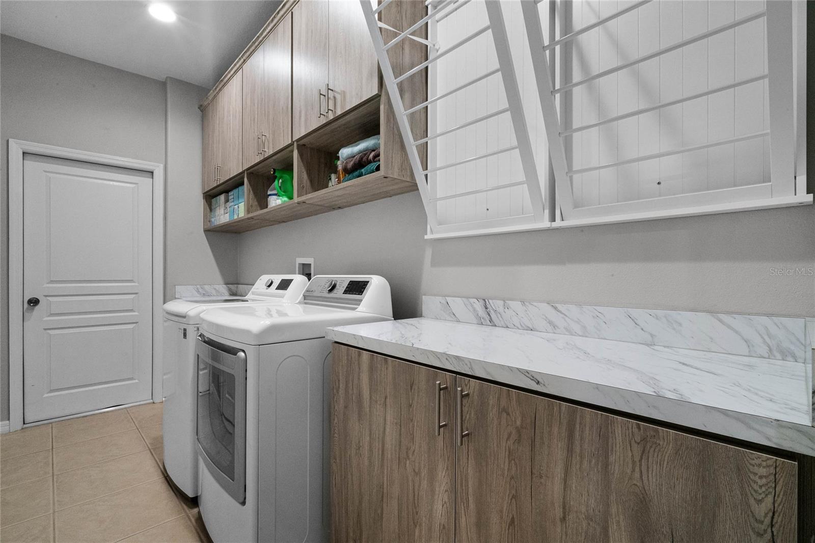 LAUNDRY ROOM: NEW CABINETS & DRYING RACKS. Ceramic Tile Flooring, Pre-Plumbed for a future sink to be installed.
