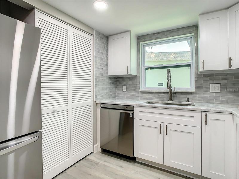 The Well-equipped Kitchen with upgraded LG stainless-steel appliances, including a convection oven with air fryer, soft close cabinets, designer marble countertops extended for a convenient breakfast bar, a stylish glass tile backsplash, an upgraded Kohler faucet, can lighting, and a spacious pantry