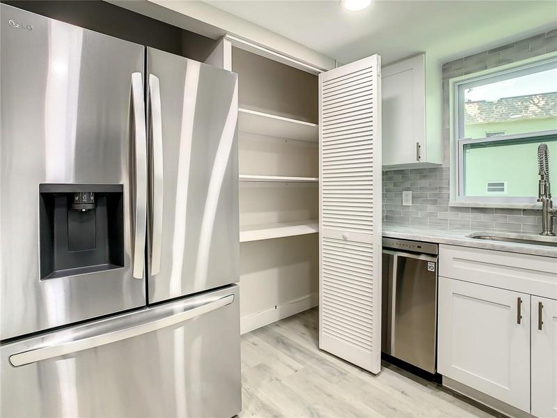 The Well-equipped Kitchen with upgraded LG stainless-steel appliances, including a convection oven with air fryer, soft close cabinets, designer marble countertops extended for a convenient breakfast bar, a stylish glass tile backsplash, an upgraded Kohler faucet, can lighting, and a spacious pantry