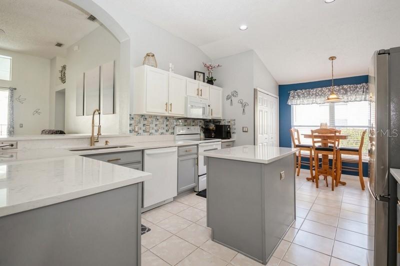 Kitchen with view to lanai from sink over breakfast bar, quartz counters, laundry closet, breakfast nook