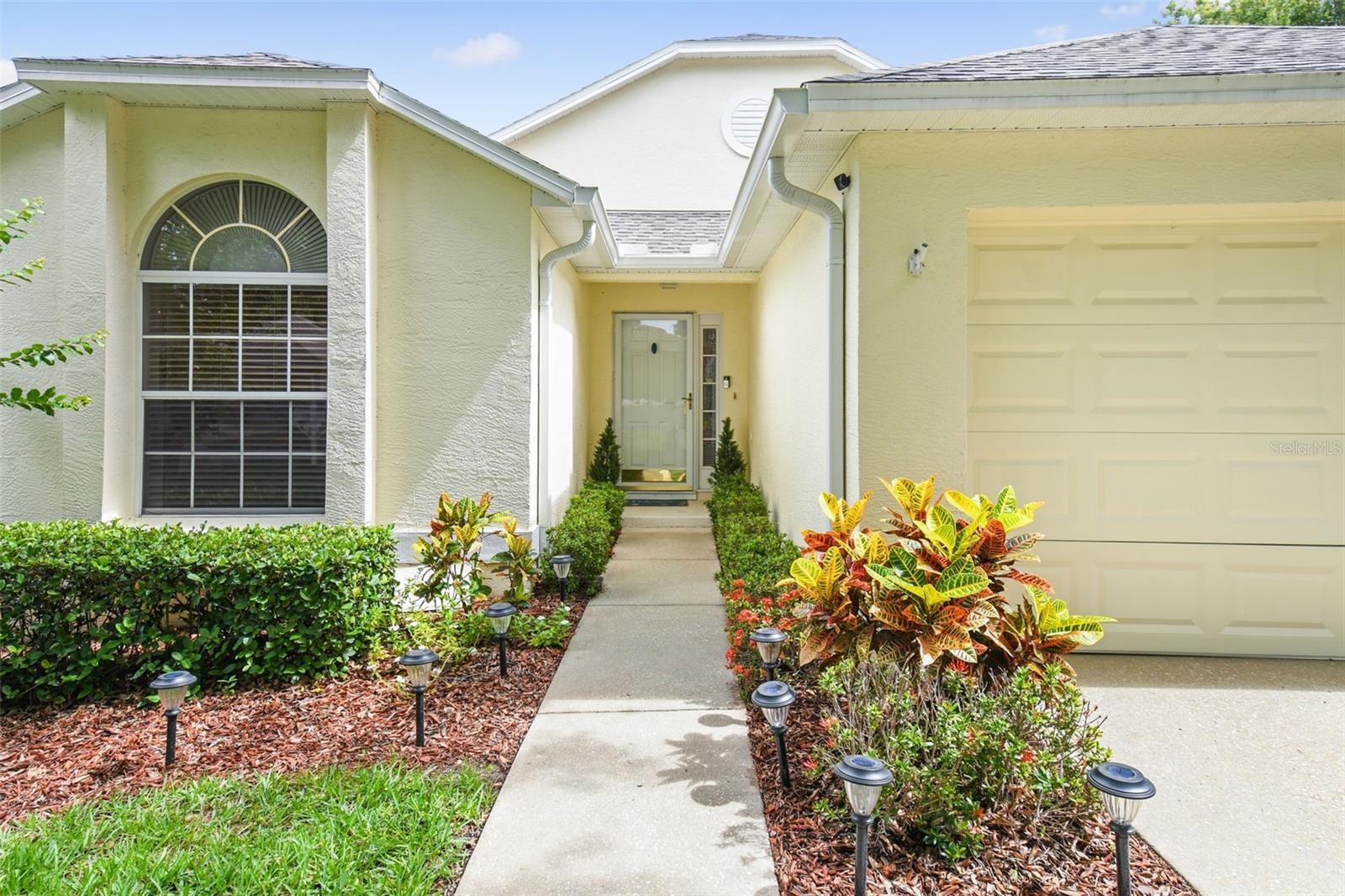Colorful foliage lines the walkway and the home's rain gutters help keep everything neat