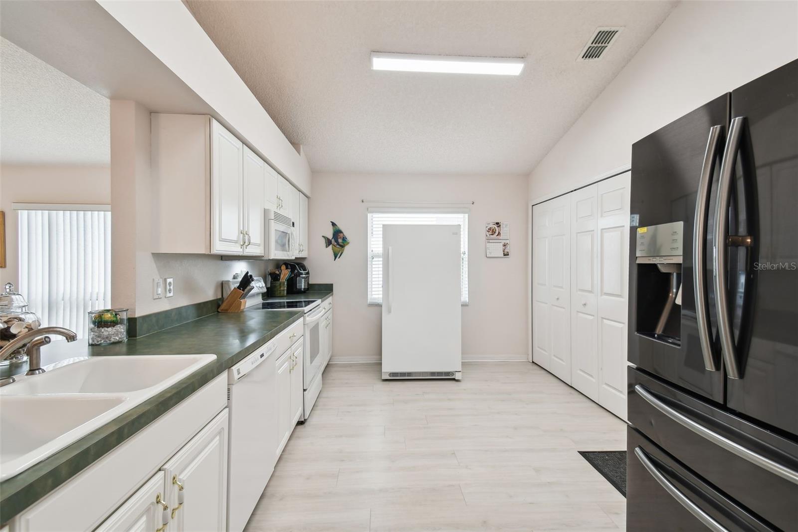 Closet doors near the window contain your laundry space and keep it tidy when not in use. The big freezer is excluded from the sale.