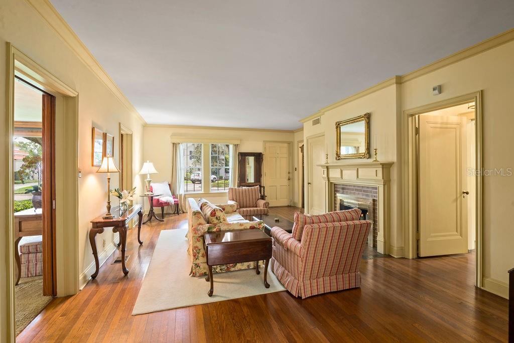 Living room with beautiful original hardwood floors, crown molding and wood-burning fireplace adds so much charm and character!