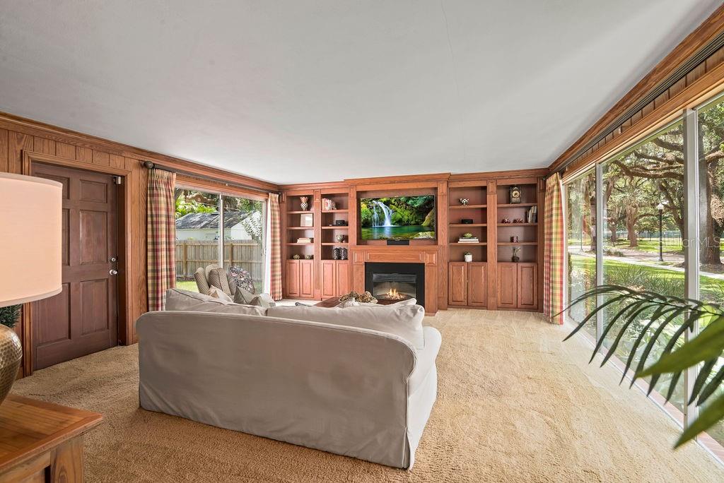 Large family room with wood paneling, electric fireplace and sliding glass doors to the oversized backyard.  Lots of natural light!  The built-ins can be removed to reveal an additional sliding glass door.