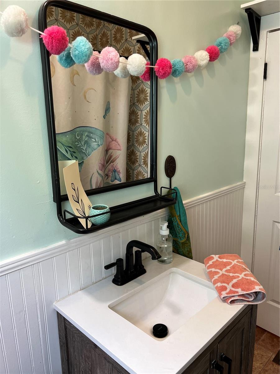 Updated bathroom with window, built-in shelving, tub and shower combo, exhaust fan and art deco style tile