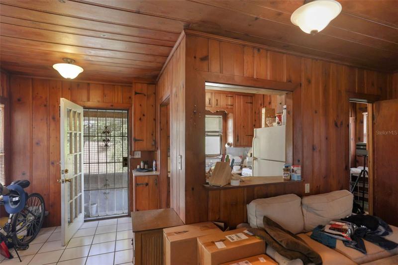Living room with view to kitchen and entrance, upper unit Building 2. Unit has original knotty pine and hardware