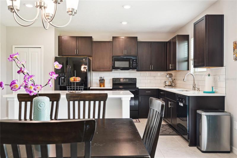 View into kitchen with quartz countertops and subway backsplash