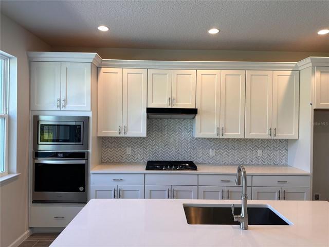Kitchen features designer backsplash and quartz countertops