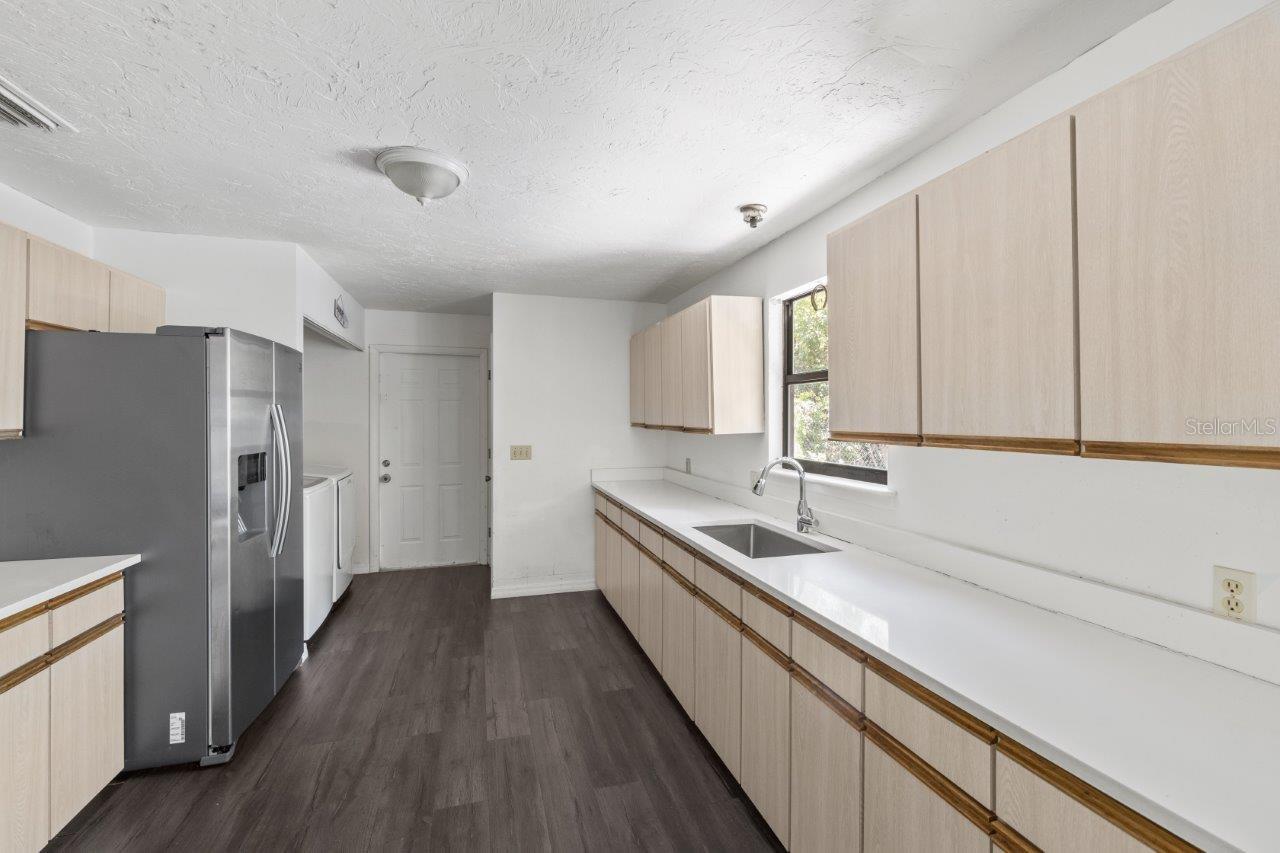 Left Unit: Beautiful kitchen featuring newer whirlpool stainless steel appliances, quartz countertops, an abundance of cabinetry, laundry closet, large pantry, and exterior door to the side yard.