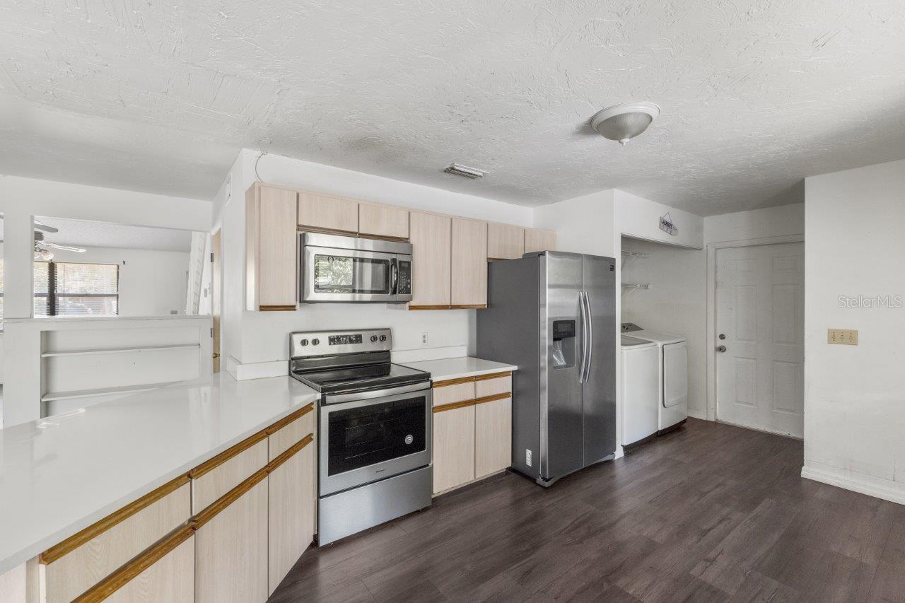 Left Unit: Beautiful kitchen featuring newer whirlpool stainless steel appliances, quartz countertops, an abundance of cabinetry, laundry closet, large pantry, and exterior door to the side yard.