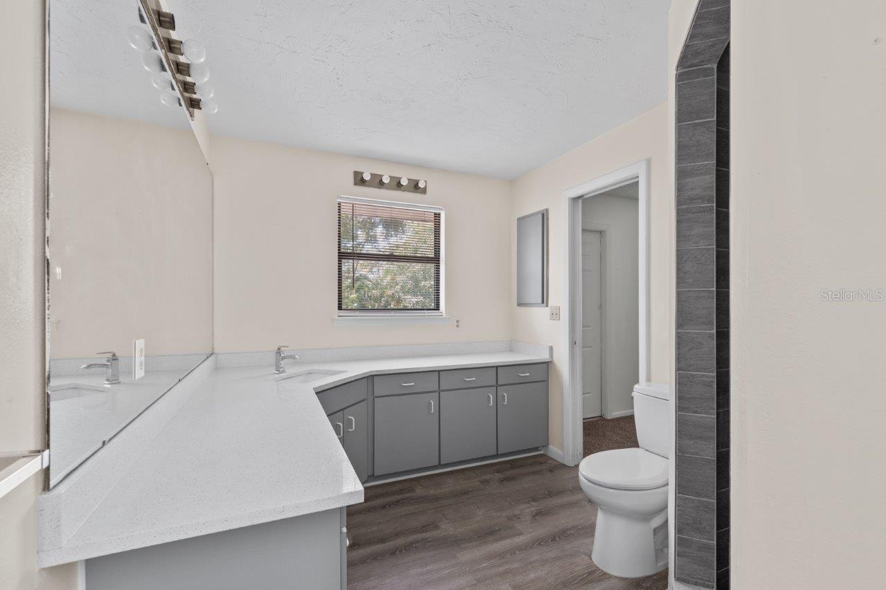 Left Unit: Guest Jack and Jill bathroom featuring quartz countertops, extended vanity, and walk-in shower.