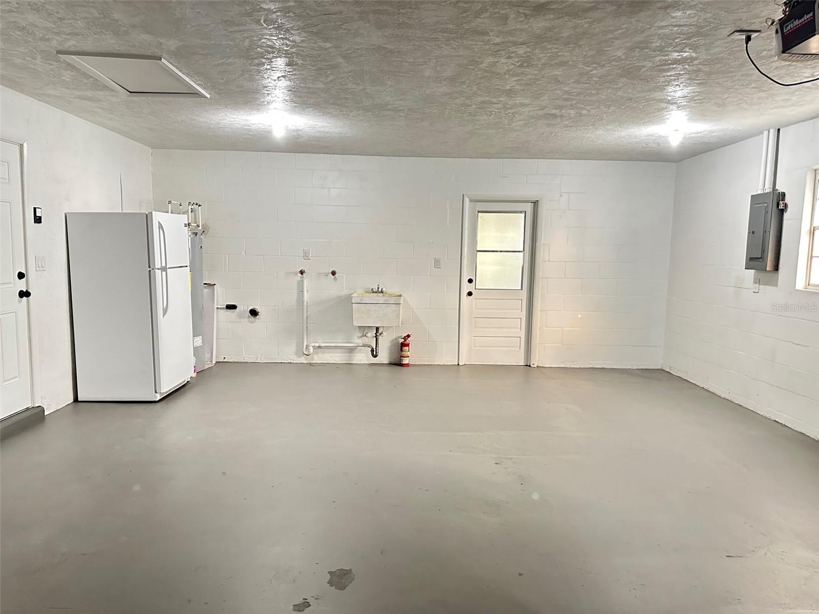 Garage with 2nd Fridge and door to back porch