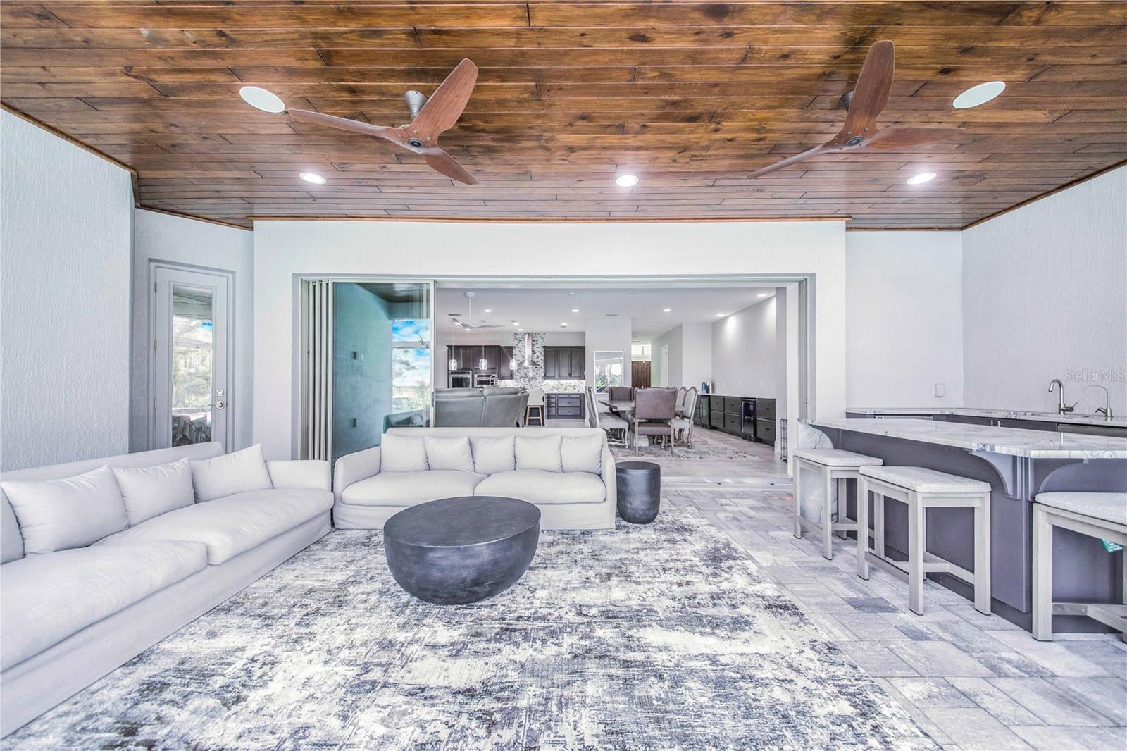 View of the Rear Porch Lounge Area with Exotic Wood Ceiling and Summer kitchen ~ opens through Pocket Sliders into the Living Area