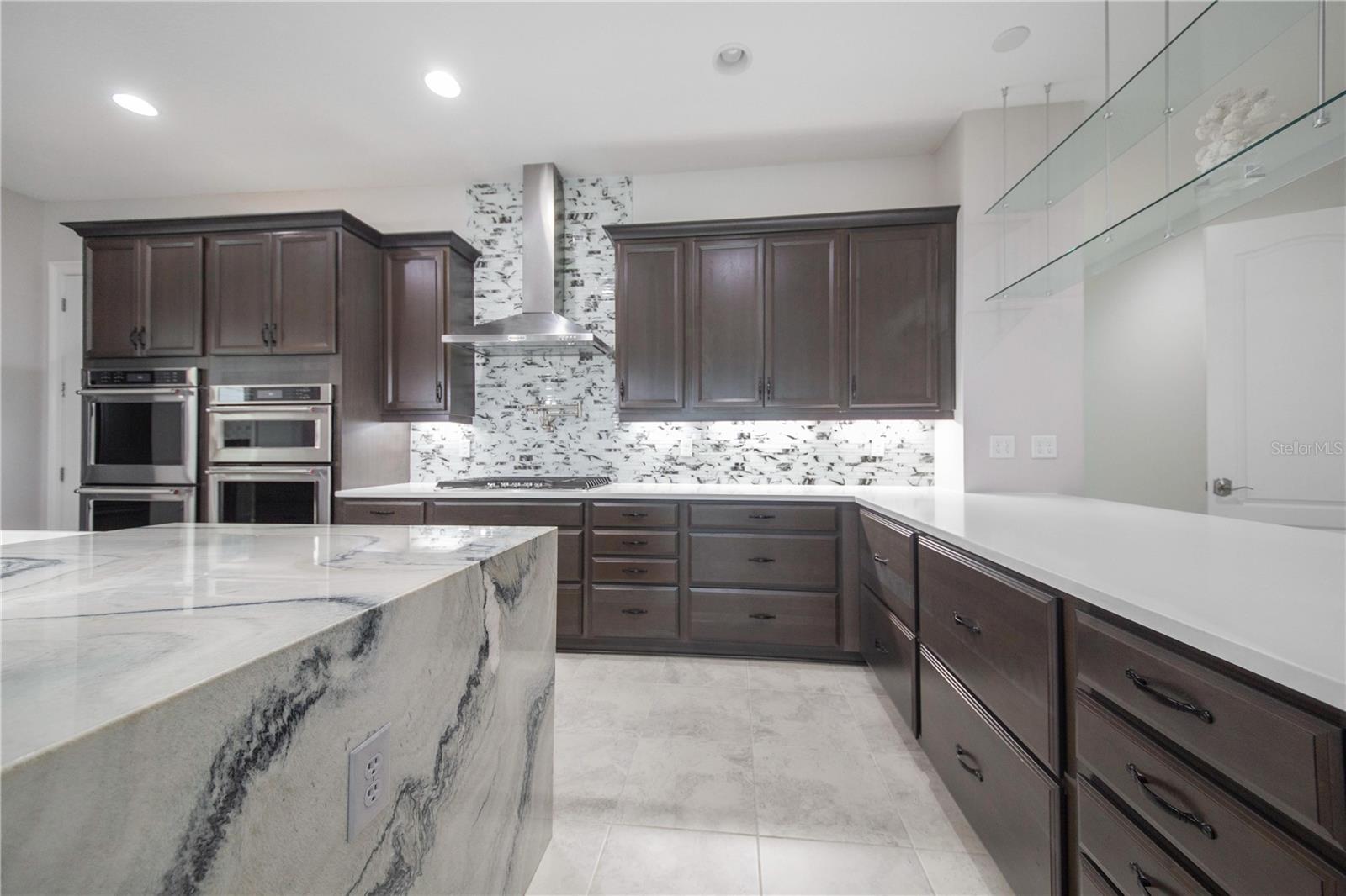 Chef's Kitchen features Waterfall Edge Quartzite Island, Pot Filler, Gas Stove with Stainless Steel Hood and Upgraded Cabinetry .