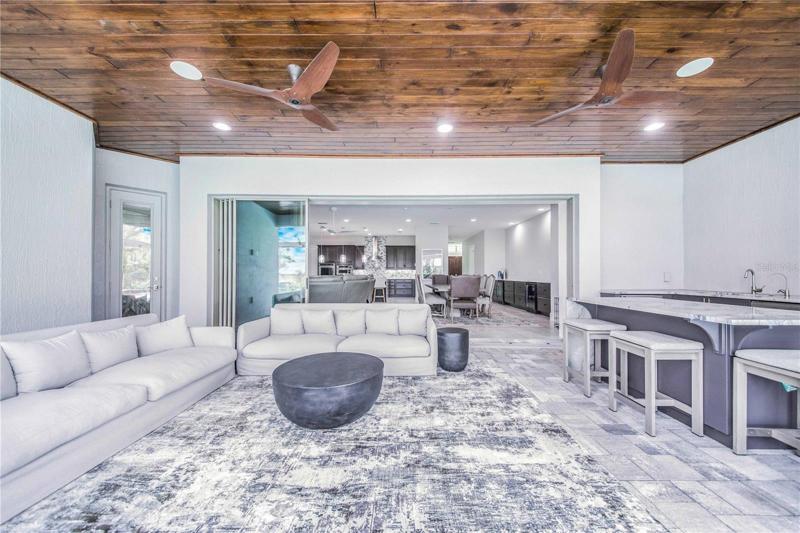 View of the Rear Porch Lounge Area with Exotic Wood Ceiling and Summer kitchen ~ opens through Pocket Sliders into the Living Area
