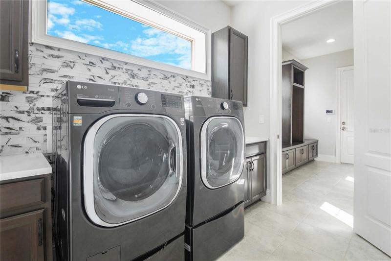 Downstairs Laundry Room is off the Kitchen with view towards Drop Zone Cabinetry in Hall and Garage entry door