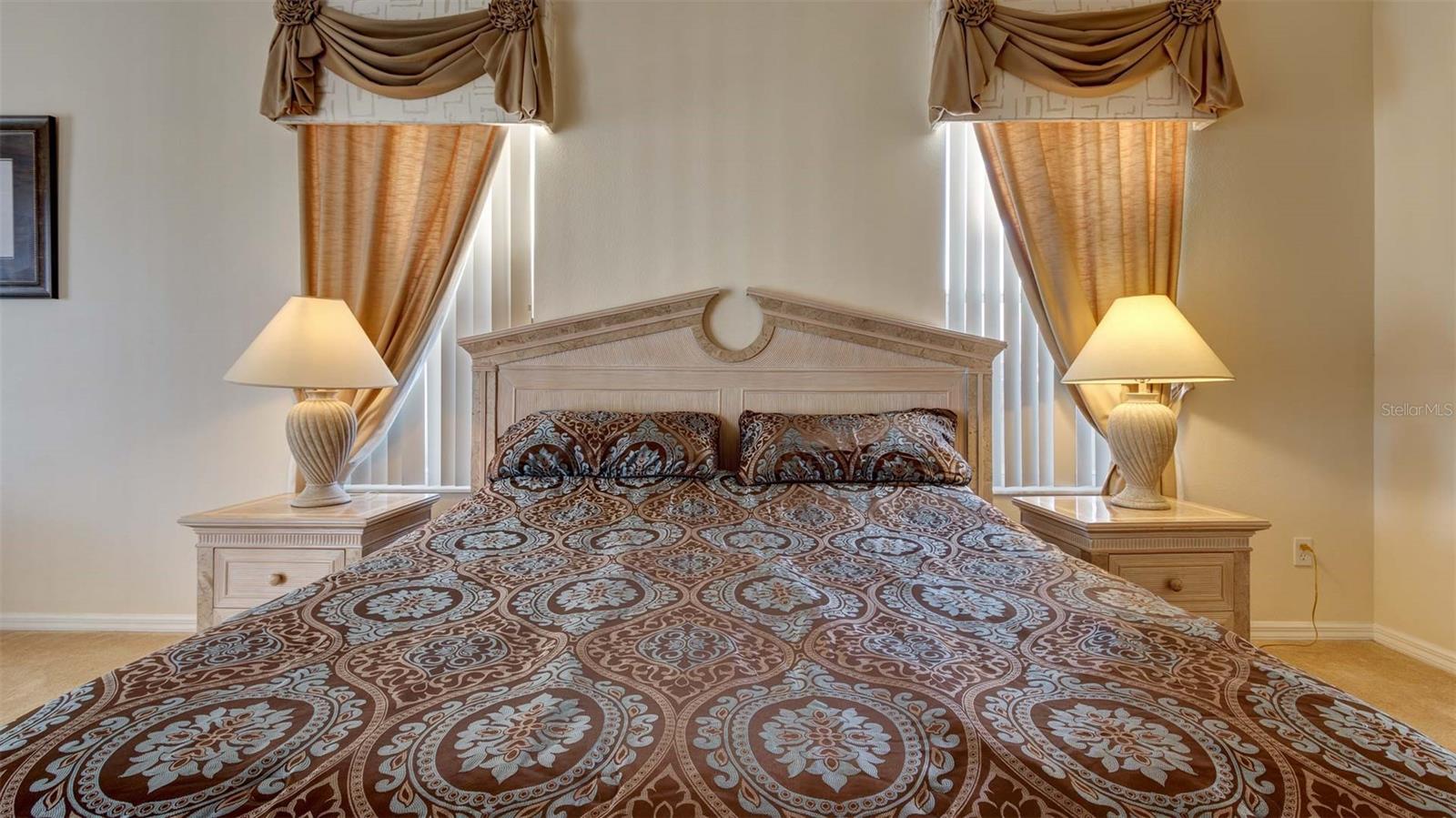 King sized bed nestled between two windows providing lots of natural light into the master bedroom