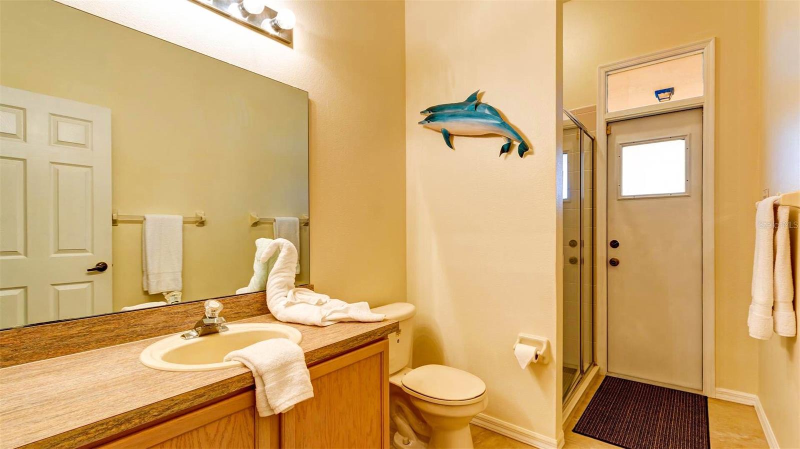 Guest bathroom with walk-in shower providing easy access onto  the covered lanai and pool area