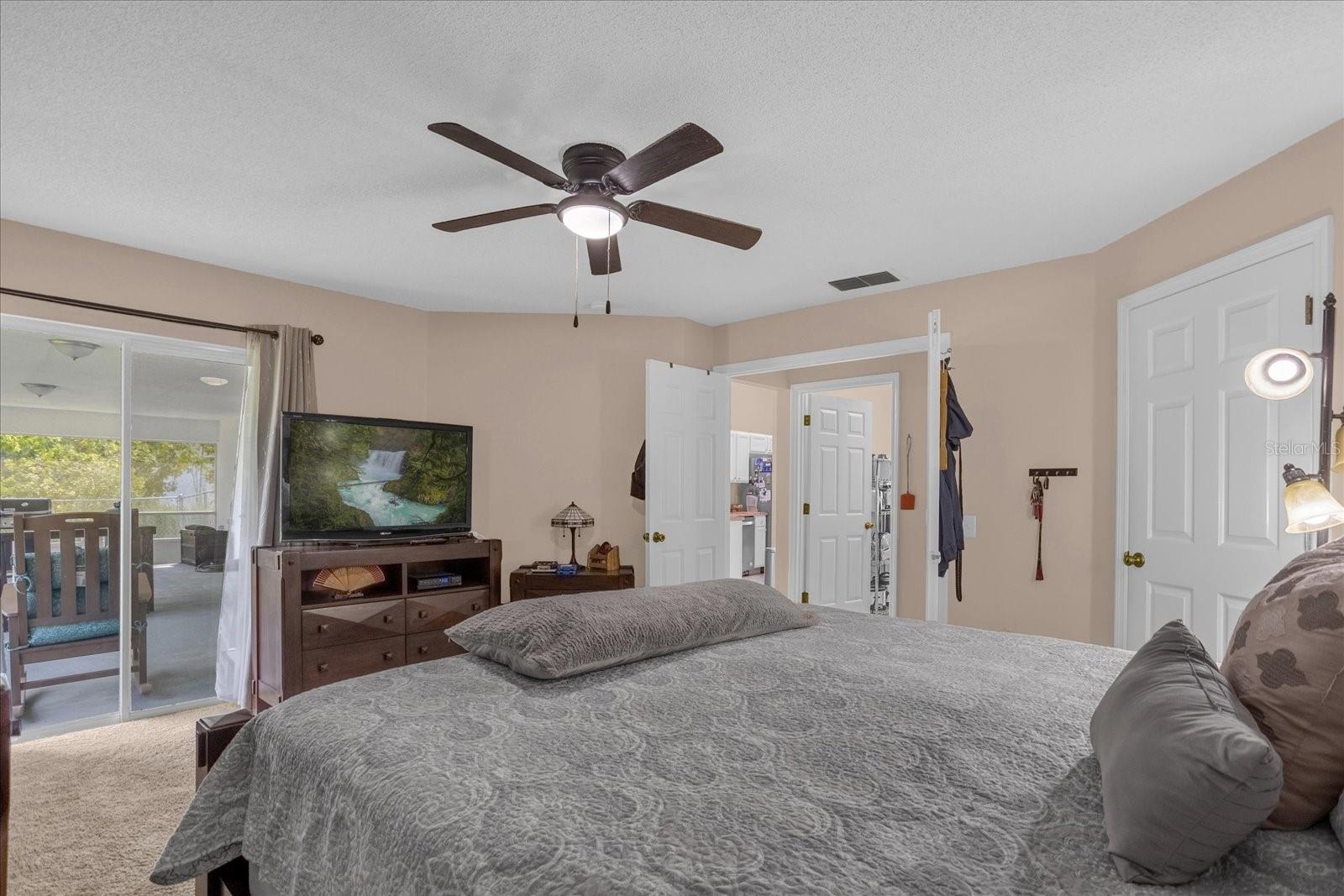 Double door entry to primary bedroom with sliders to the screened patio.