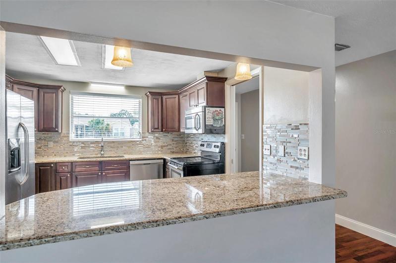 Spacious, open kitchen with granite countertops, Large, Undermount Sink with Window above, Cherry cabinets, Stainless Steel Appliances, and a pass through countertop bar to the Dining Room.