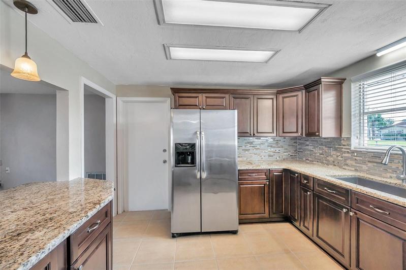 Spacious, open kitchen with granite countertops, Large, Undermount Sink with Window above, Cherry cabinets, Stainless Steel Appliances, and a pass through countertop bar to the Dining Room.