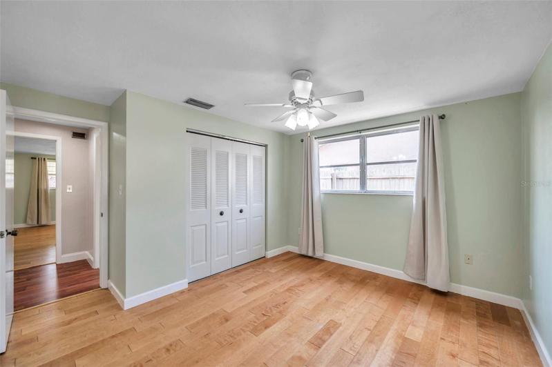 Secondary bedroom with lots of natural light, ceiling fan, curtain rods and drapes.