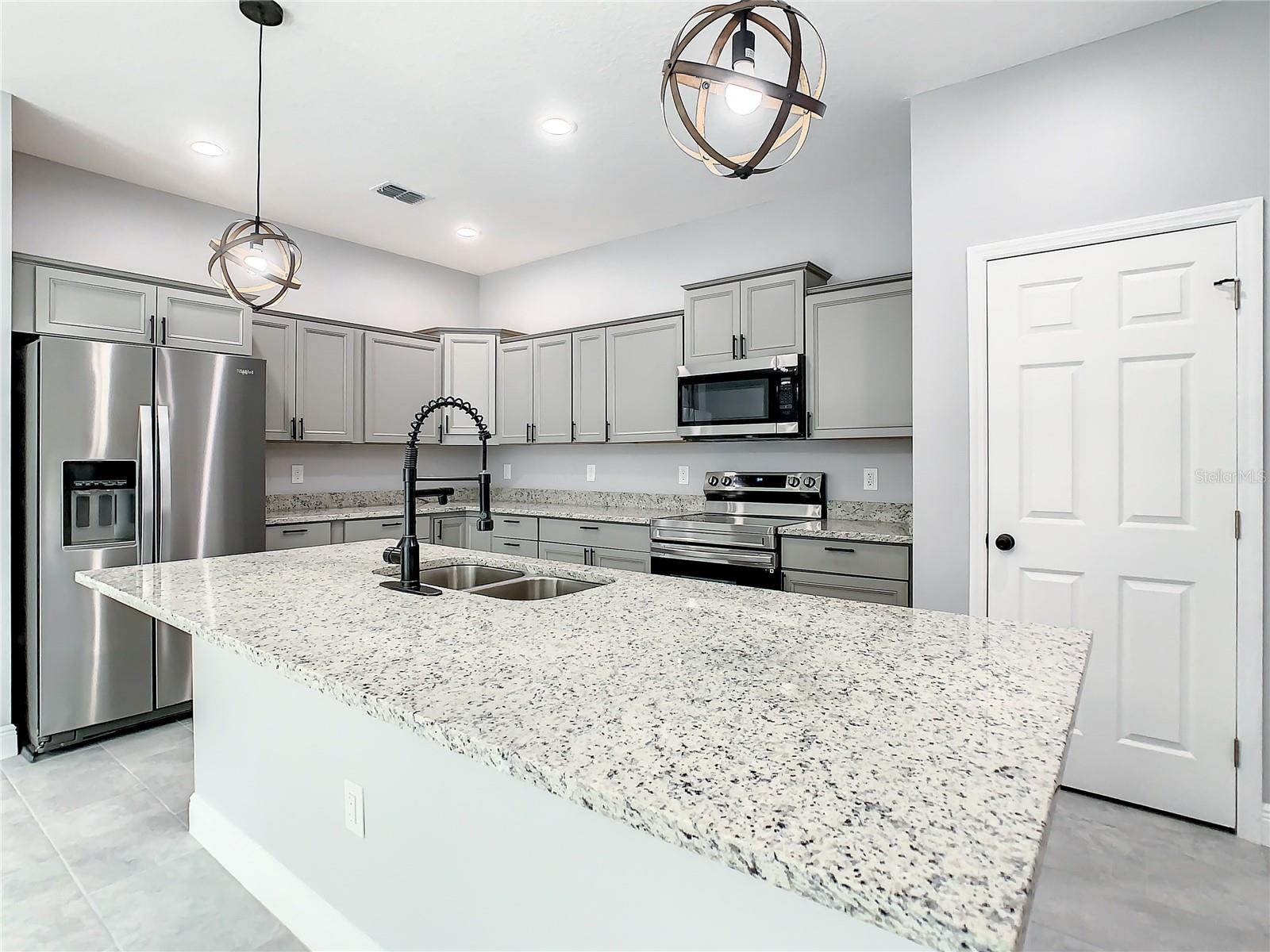 Granite Counter tops with upgraded staggered cabinets with crown molding in kitchen and Large breakfast bar