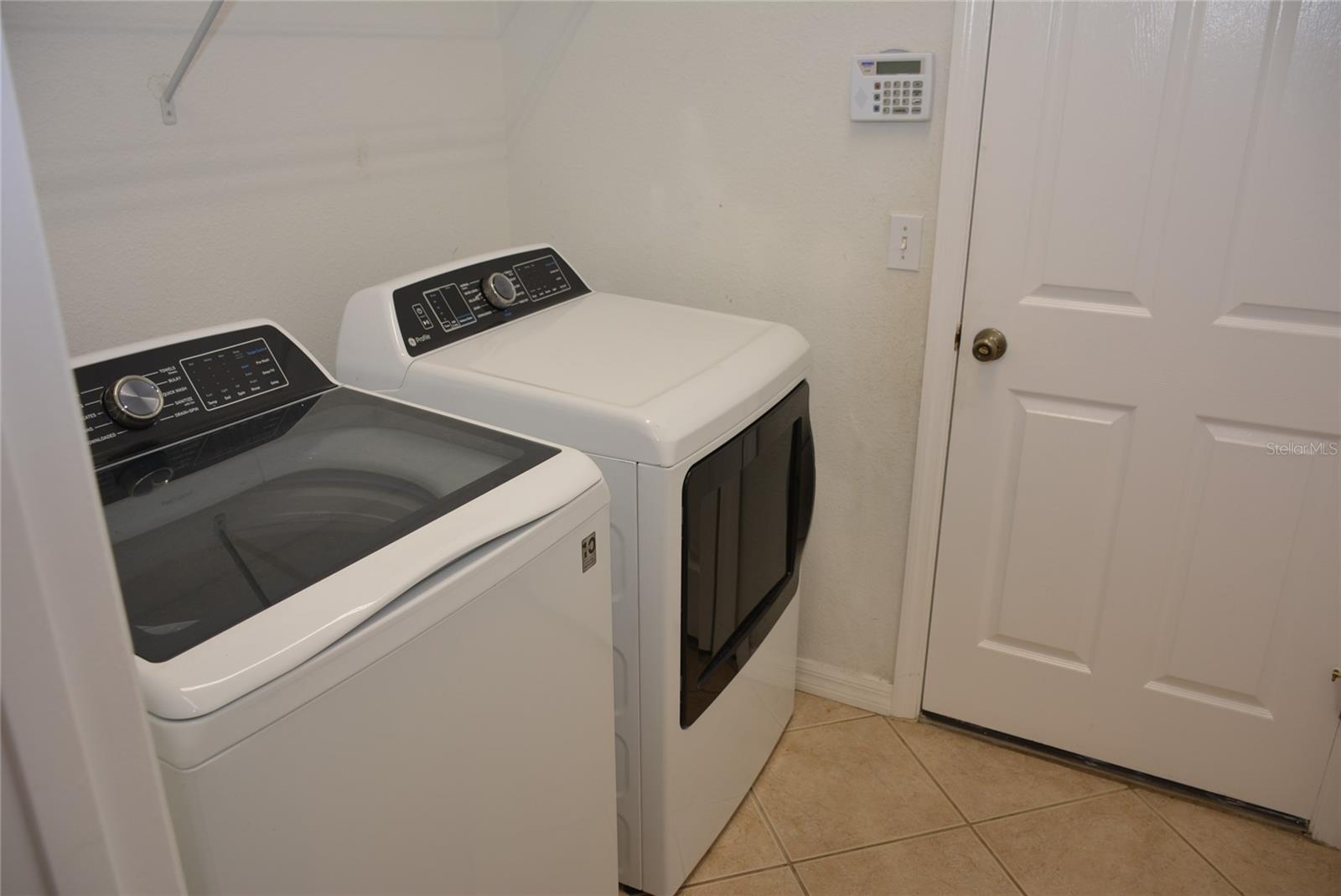 Utility room with washer, dryer and oversize double closet located between the kitchen and the garage