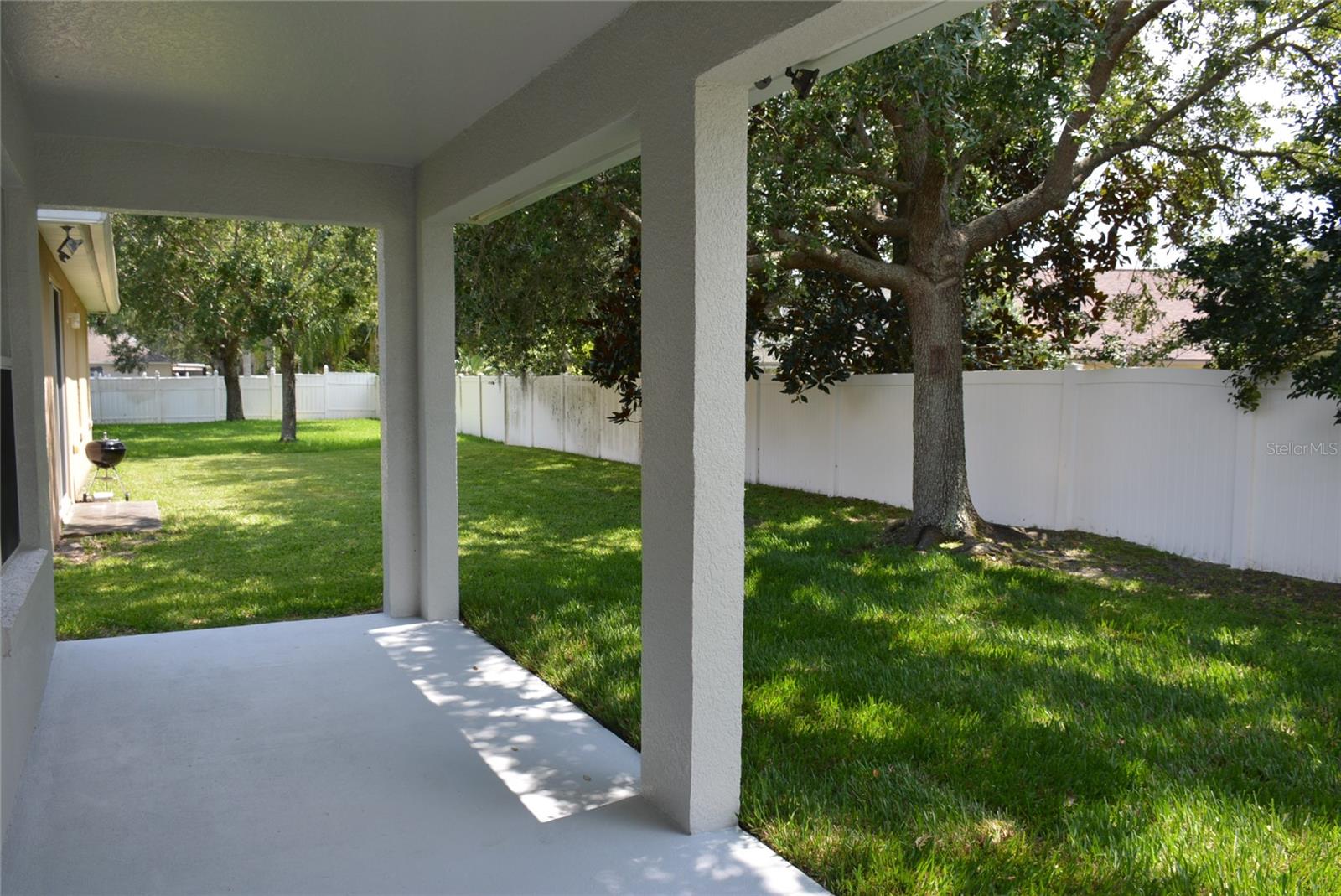 Covered lanai leads to partially fenced backyard