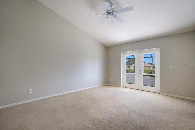 Primary bedroom with vaulted ceilings and french doors leading to pool area