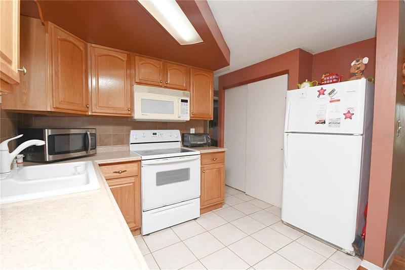 The kitchen features wood cabinets, ceramic tile flooring and a large closet pantry.