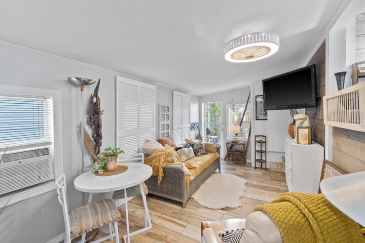 Living room featuring wood look tile flooring, shiplap walls, and access to the rear lanai