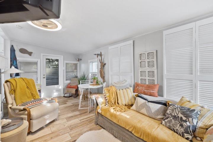 Living room featuring wood look tile flooring, shiplap walls, and access to the front lanai