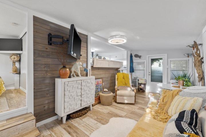 Living room featuring wood look tile flooring, shiplap walls, and access to the front lanai