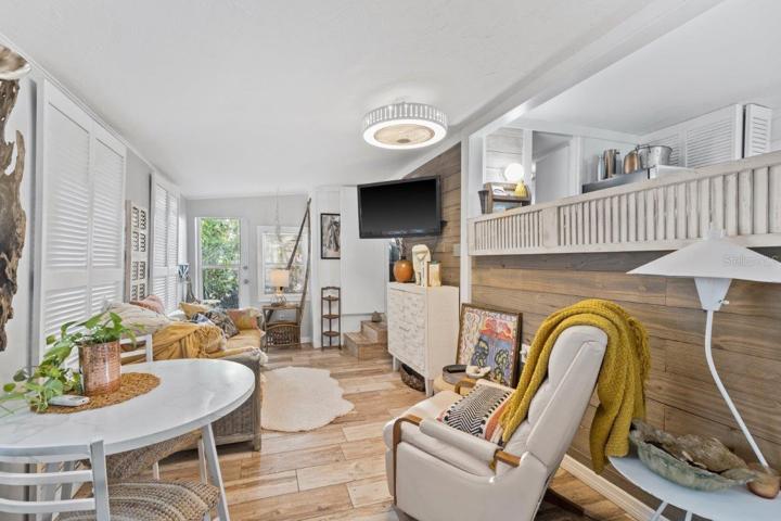 Living room featuring wood look tile flooring, shiplap walls, and access to the rear lanai