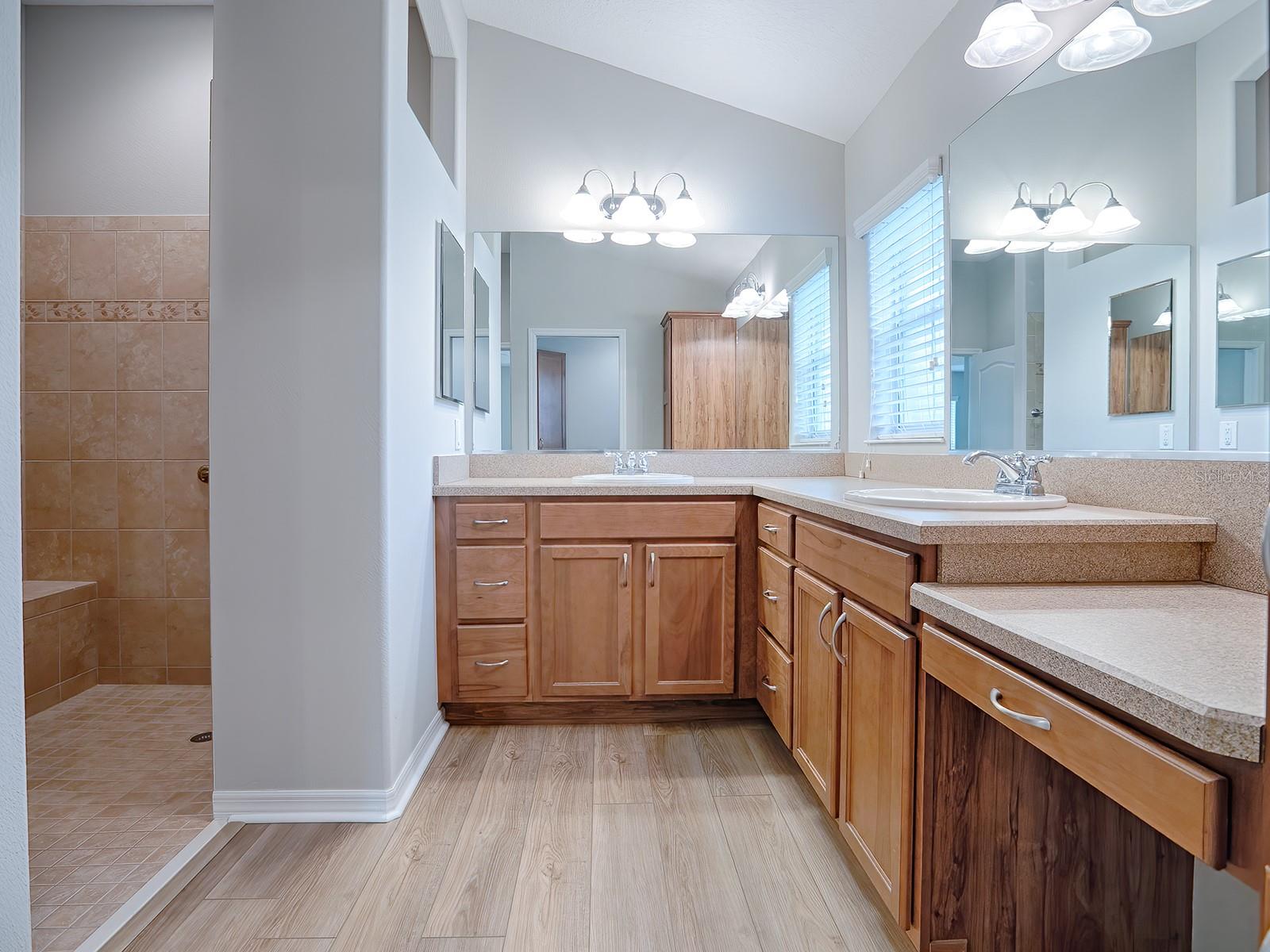 EN SUITE MASTER BATH WITH DUAL SINKS, VANITY AREA, ROMAN SHOWER, AND SEPARATE TOILET ROOM.