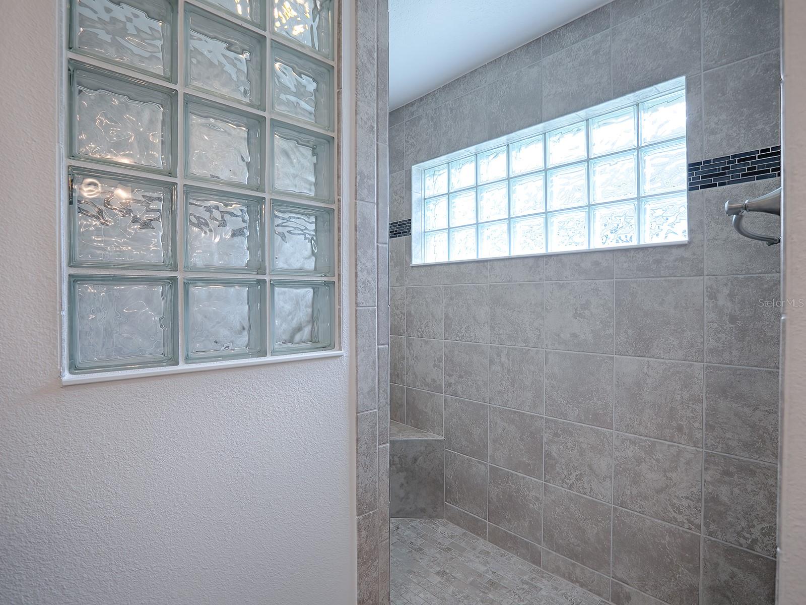 ROMAN WALK-IN SHOWER WITH GLASS BLOCK WINDOW ALLOWING FOR LOTS OF NATURAL LIGHT.