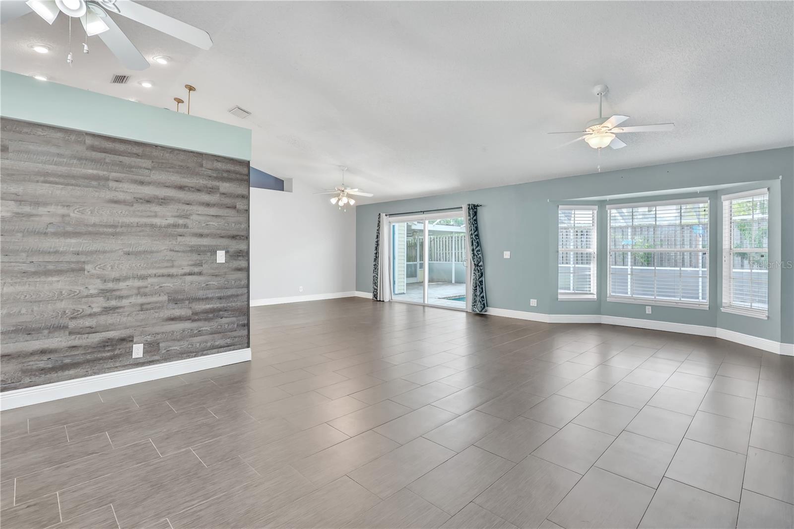 Entering the Home you see the Open Floor Plan. Family Room, Living Room, Dining Room and Kitchen, all open. Home Office was set against the wood plank wall.