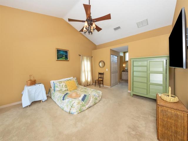 Large primary bedroom has cathedral ceilings, sliders to the lanai and pool area and two walk in closets