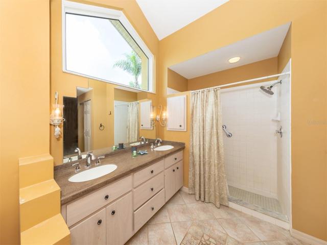Large primary bathroom features high ceilings, light from above, dual sink vanity and large shower.