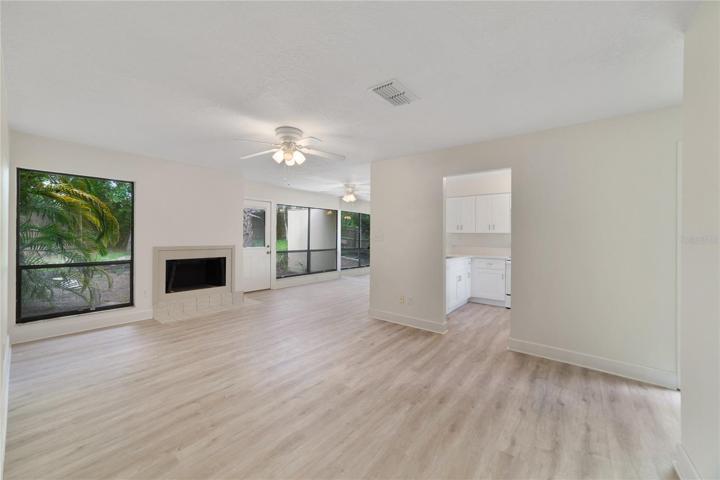 Living room and dining room with wall of windows overlooking backyard and patio