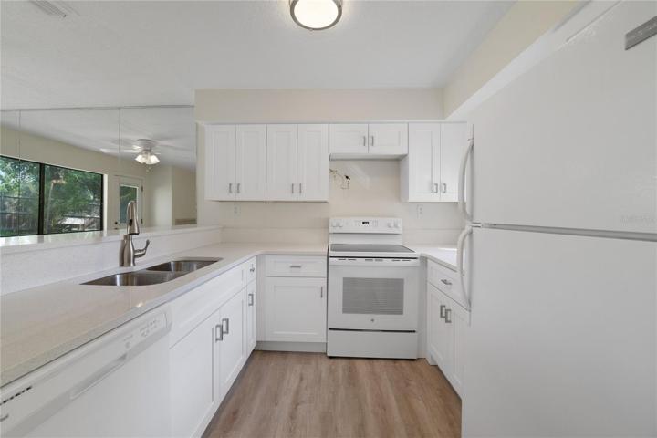 Newly remodeled kitchen with white shaker cabinets, dishwasher, disposal, double basin sink, range, refrigerator and quartz countertops.